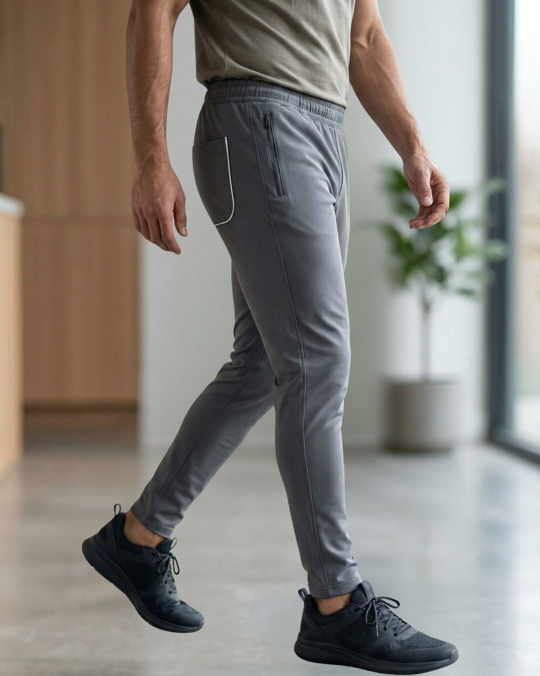 Man wearing slim-fit grey track pants with zip pocket in modern indoor setting