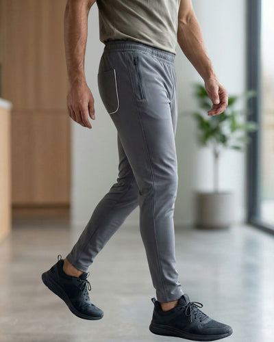 Man wearing slim-fit grey track pants with zip pocket in modern indoor setting