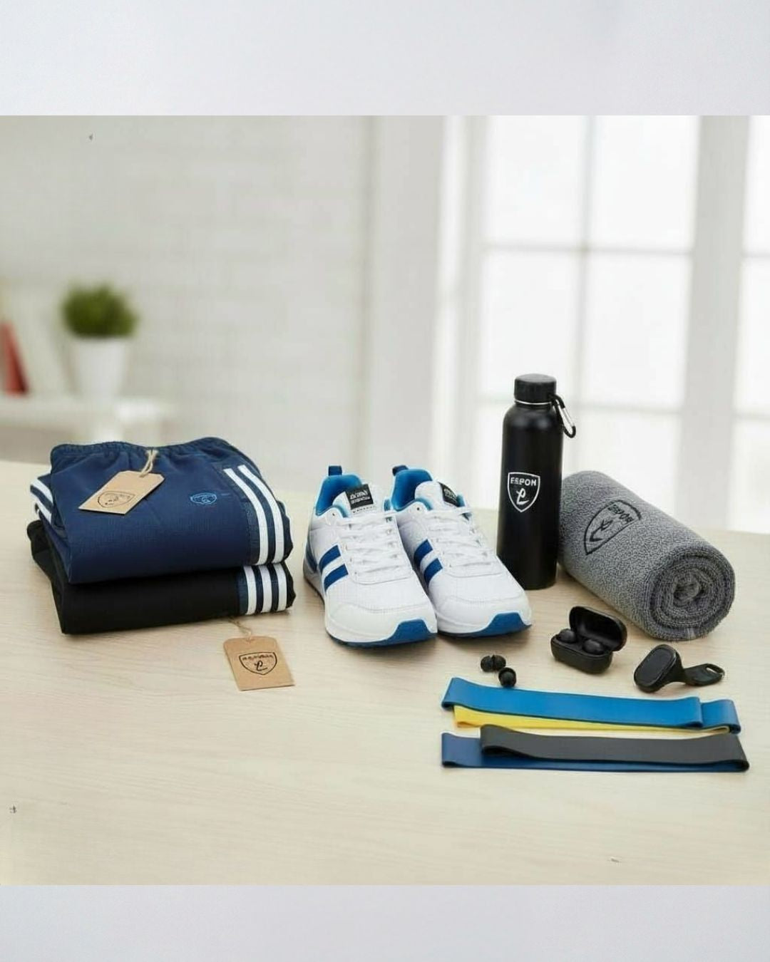 Activewear set with blue track pants, white running shoes, water bottle, towel, earbuds, and resistance bands on a table