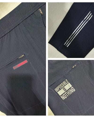 Men's navy blue track pants with zipper pockets, white stripes, and motivational print details.