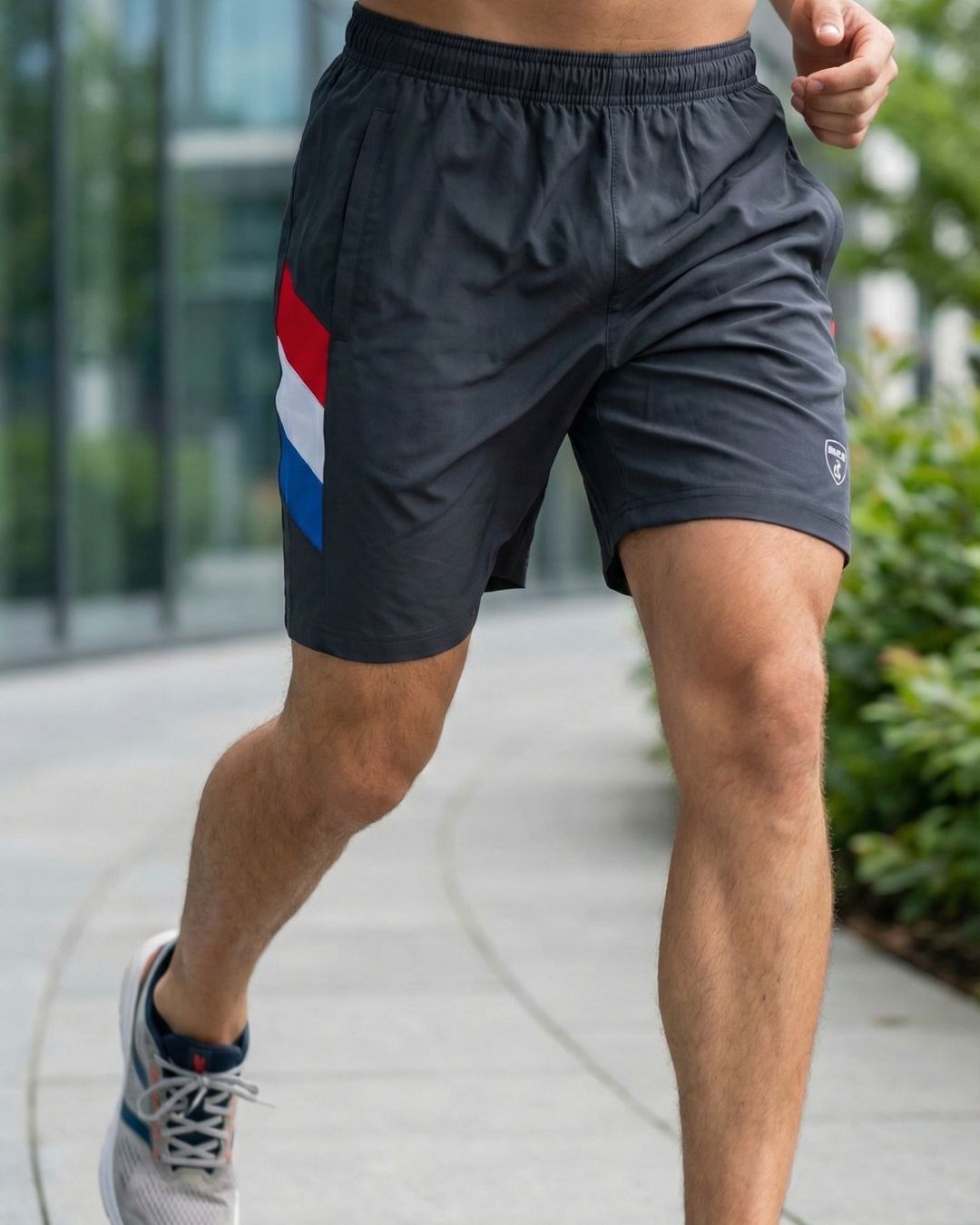 Man jogging outdoors in black athletic shorts with red, white, and blue side stripes
