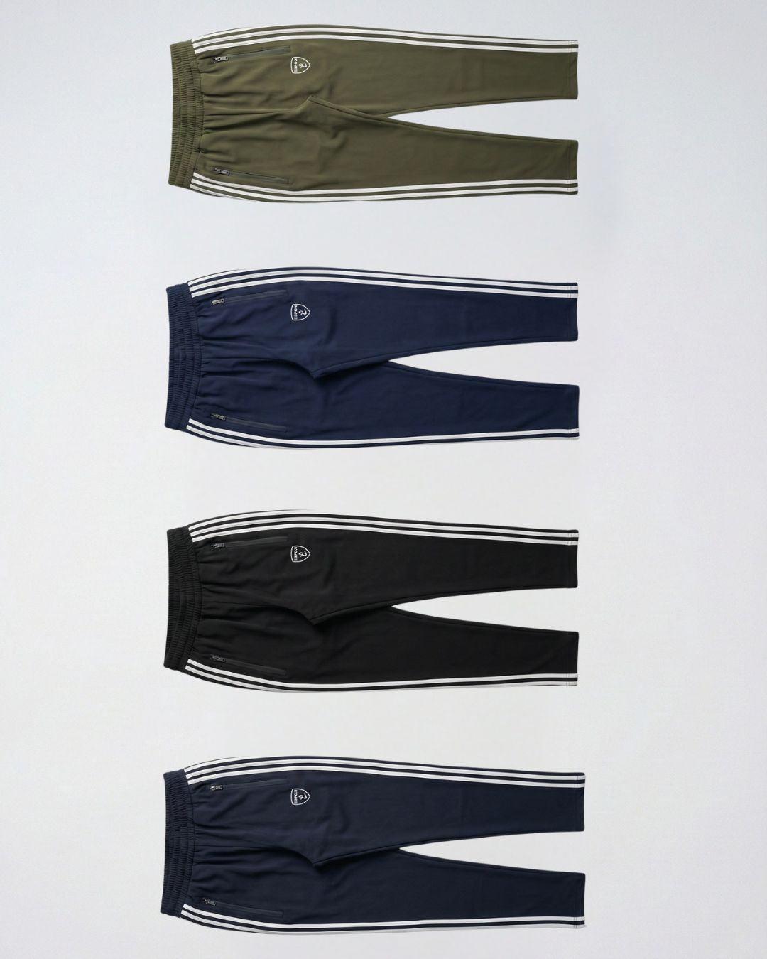 Four men's track pants in olive, navy, black, and blue with white side stripes, flat lay