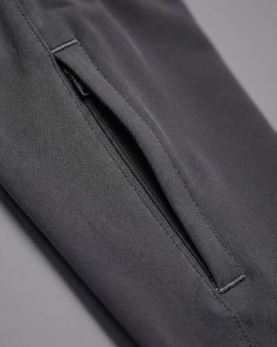 Close-up of black track pants with a zippered side pocket on gray background