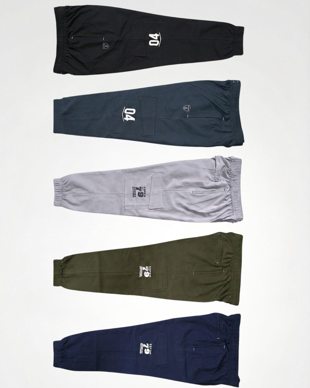 Assorted men's track pants in black, blue, grey, olive, and navy with cargo pockets and sporty prints
