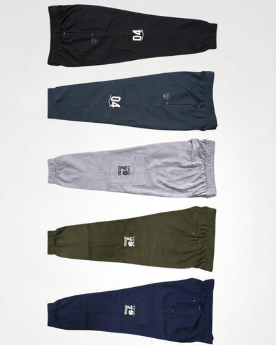 Assorted men's track pants in black, blue, grey, olive, and navy with cargo pockets and sporty prints