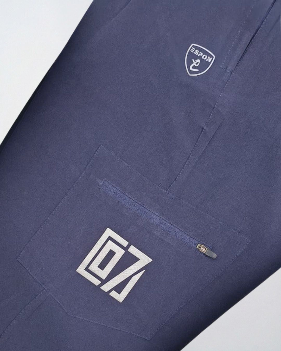 Close-up of navy blue track pants with zippered pocket and modern activewear logo