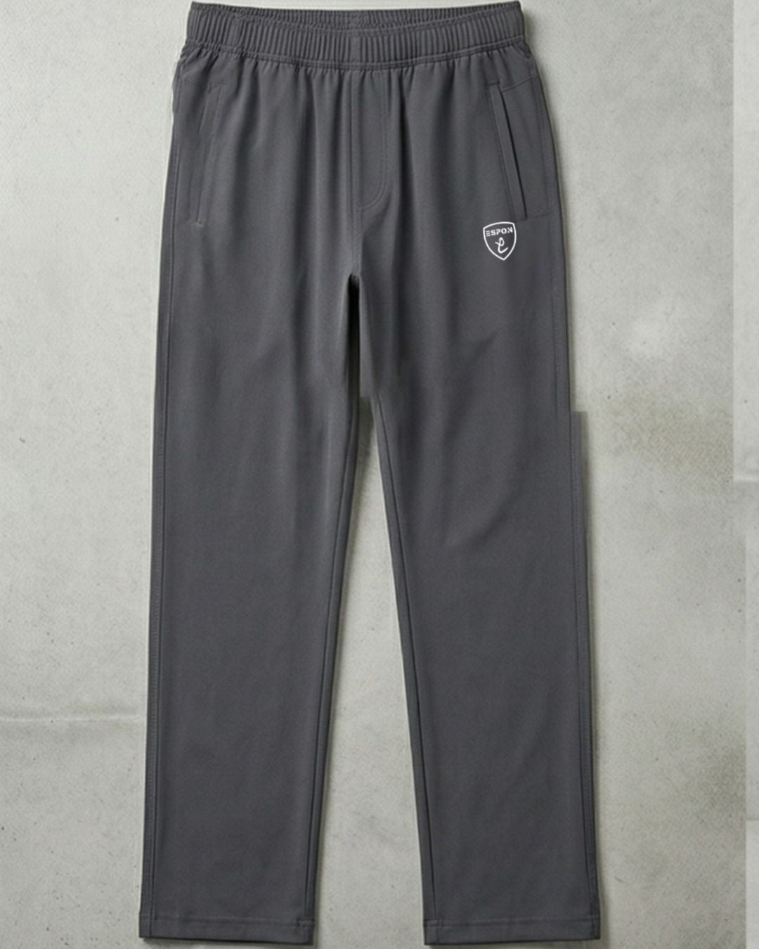 Gray athletic track pants with side pockets and elastic waistband on a concrete background