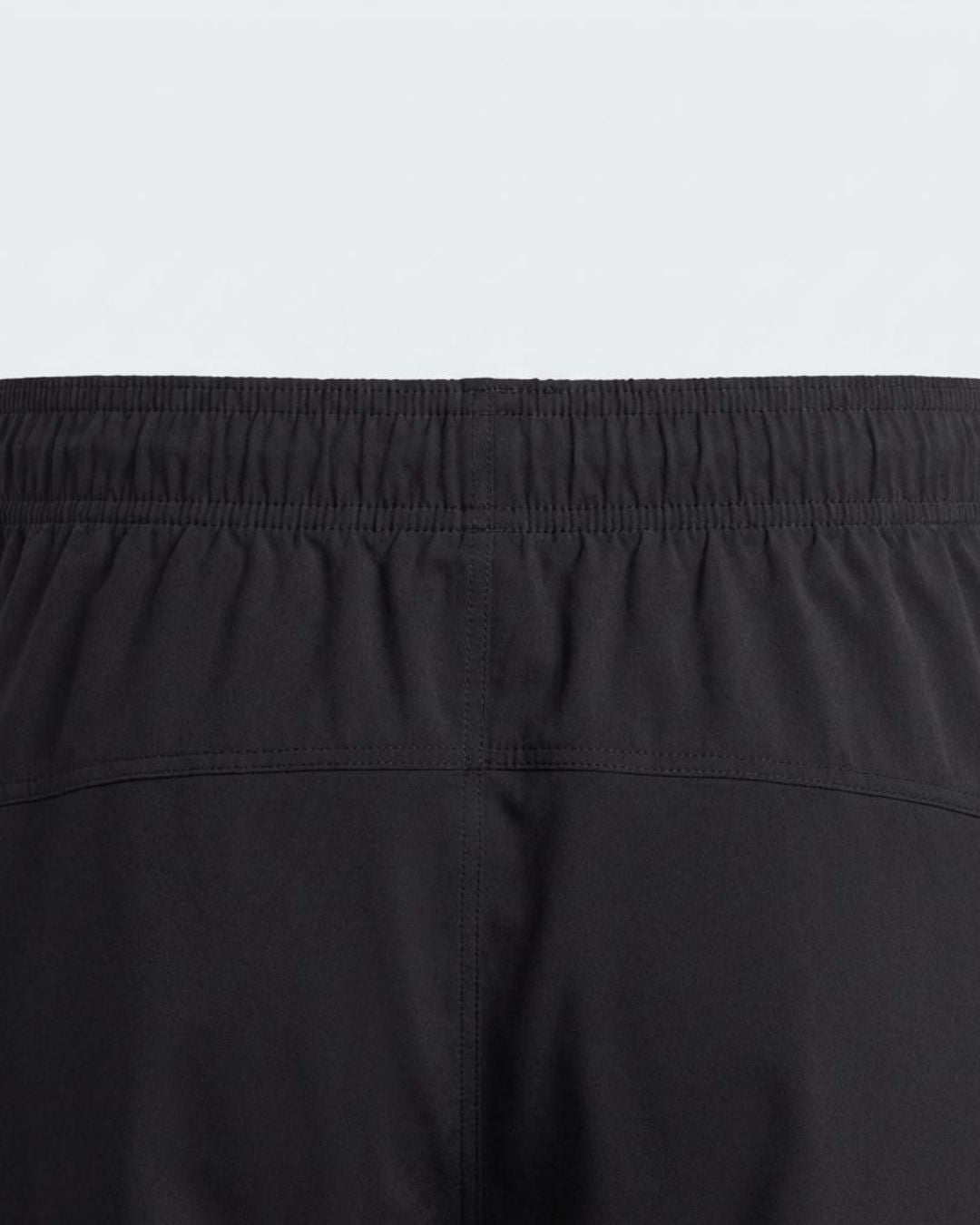 Close-up of black track pants with elastic waistband and stitched seam detail