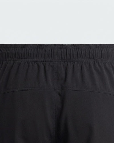 Close-up of black track pants with elastic waistband and stitched seam detail