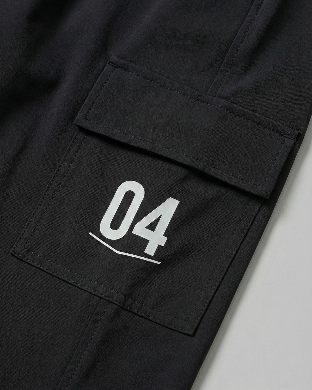 Black track pants with side cargo pocket and white number 04 print, activewear detail