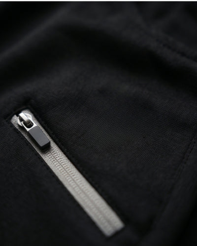 Close-up of black track pants with a silver zipper pocket, activewear textile detail