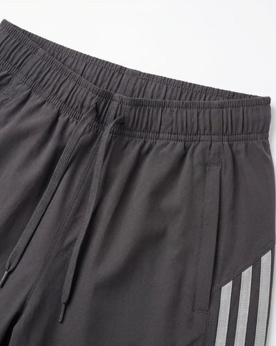 Dark grey track pants with elastic waistband, drawstring, side pockets, and reflective stripes