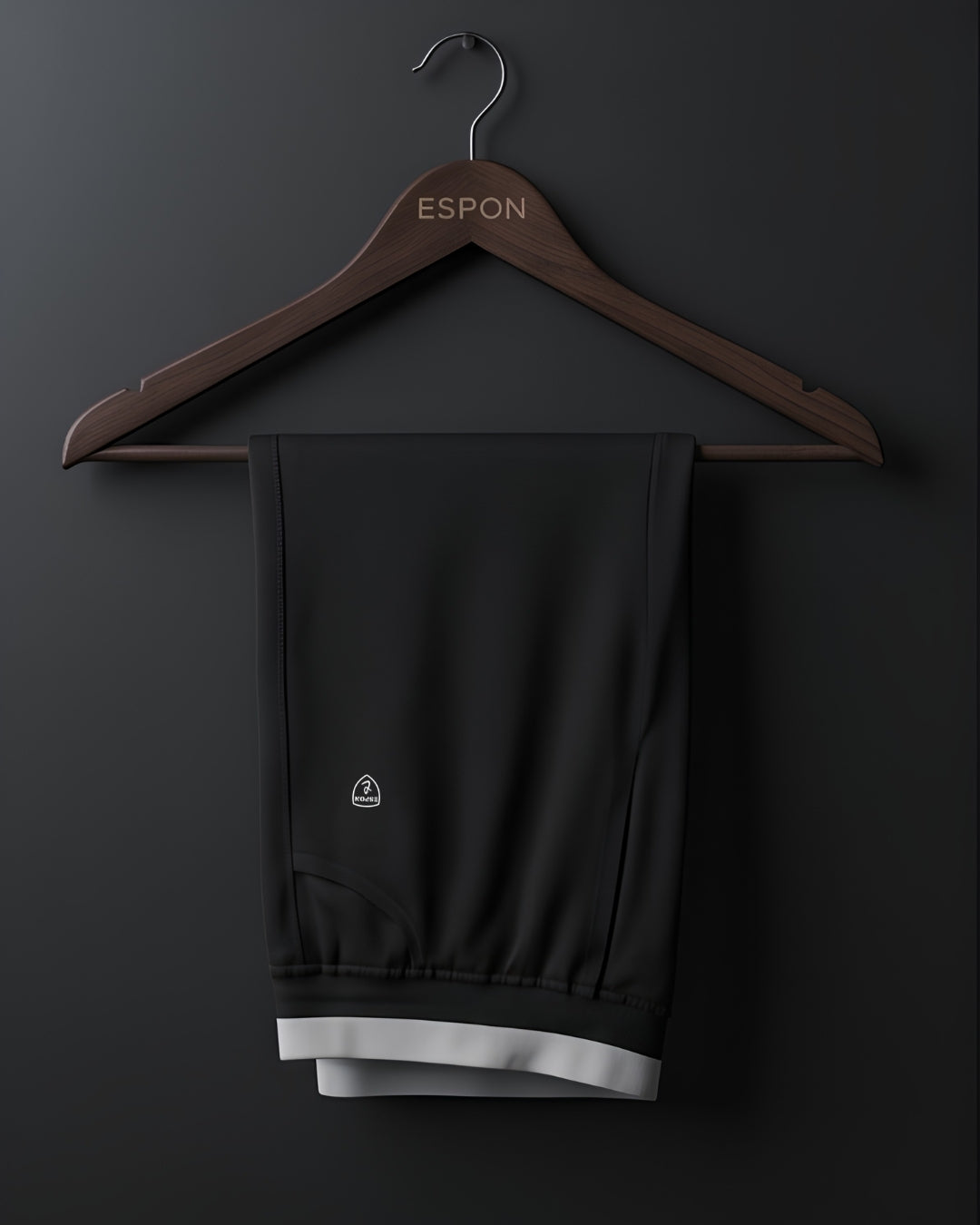 Black track pants with white trim on wooden hanger against dark background, activewear display